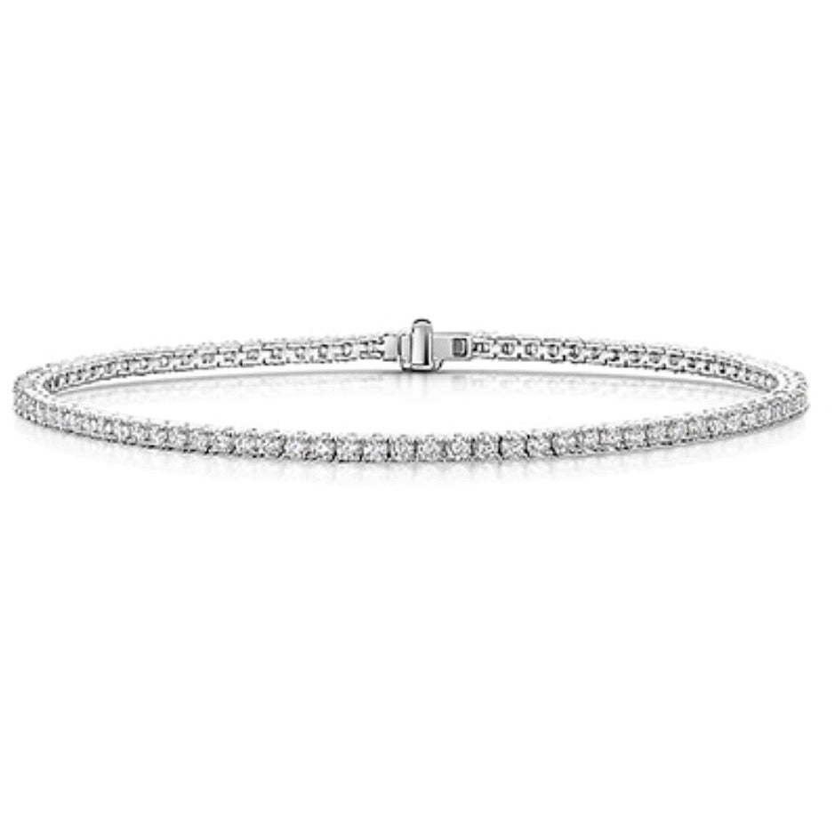 A thin silver tennis bracelet with a single row of sparkling diamonds, displayed horizontally against a clean white background.